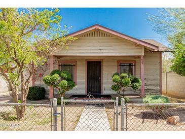 Charming exterior view of the home with a fenced yard and mature landscaping at 1029 E Mckinley St, Phoenix, AZ 85006