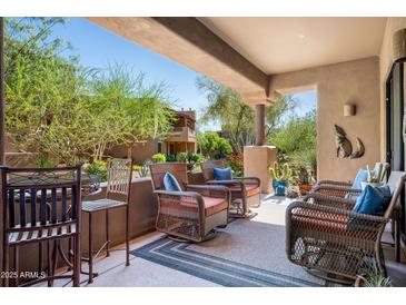 Relaxing covered patio with wicker chairs, desert decor, and views of the landscaped surroundings at 13300 E Via Linda Dr # 1058, Scottsdale, AZ 85259