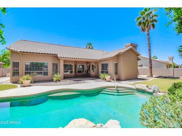 Inviting backyard pool with lush landscaping, rock features, and view of house and patio at 1470 W Bartlett Way, Chandler, AZ 85248