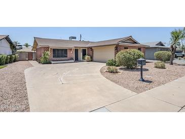 Charming single-story brick home with a large driveway and well-maintained landscaping at 8713 E Sage Dr, Scottsdale, AZ 85250