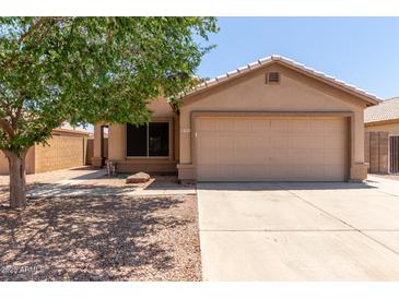Charming single-story home featuring a two-car garage, landscaped yard and mature shade tree on a sunny day at 9243 W Brown St, Peoria, AZ 85345