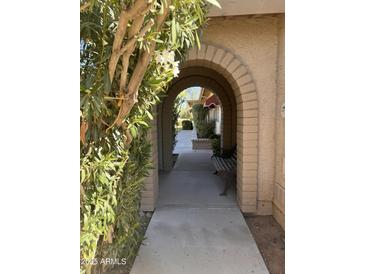 Inviting arched walkway with brick accents leads to a charming bench and landscaped entryway at 10102 E Michigan Ave, Sun Lakes, AZ 85248