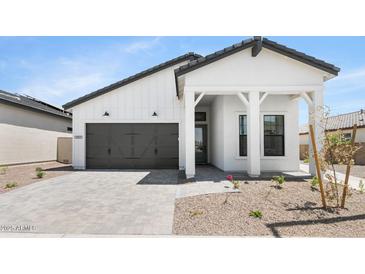 Charming white home featuring a gray garage door, covered porch, and desert landscaping at 4451 N 203Rd Ave, Buckeye, AZ 85396