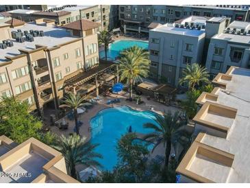 Aerial view of a resort-style pool area with palm trees and lounge chairs surrounded by multi-story buildings at 5450 E Deer Valley Dr # 2191, Phoenix, AZ 85054
