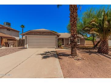 Charming single-story home featuring a well-maintained lawn, mature trees, and a two-car garage at 7426 W Cholla St, Peoria, AZ 85345