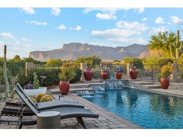 Lounge by the refreshing pool with water features and desert mountain views, perfect for relaxation at 7846 E Wilderness Trl, Gold Canyon, AZ 85118
