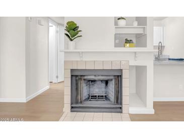 Cozy fireplace with white tile surround and wood flooring, perfect for a relaxing ambiance at 1126 W Elliot Rd # 2023, Chandler, AZ 85224
