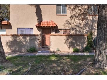 Inviting front entrance with a red tile awning, decorative wrought iron gate, and lush desert landscaping at 14404 N Boxwood Ln, Fountain Hills, AZ 85268
