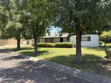Quaint single story home with a well maintained lawn and established shade trees at 1447 E Town And Country Ln, Phoenix, AZ 85014