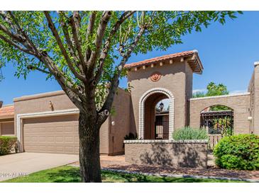 Inviting beige home featuring an arched entrance, red tile roof, and mature landscaping with trees at 25230 S Berry Brook Dr, Sun Lakes, AZ 85248