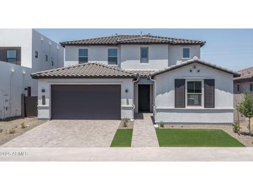 Charming two-story home featuring a gray tiled roof, brick driveway, and a neatly manicured lawn at 7944 W Griswold Rd, Peoria, AZ 85345