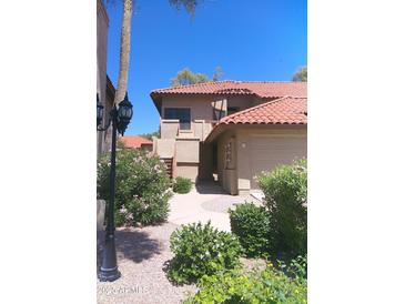 Charming two-story home featuring a red tile roof, an attached garage, and lush landscaping with vibrant flowering bushes at 8700 E Mountain View Rd # 2029, Scottsdale, AZ 85258