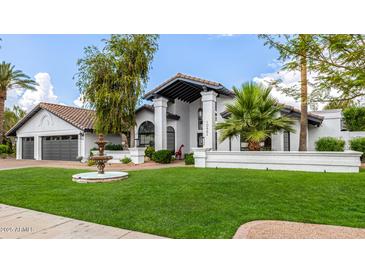 Stunning two-story home featuring lush landscaping, a decorative fountain, and a charming architectural design at 10662 E Carol Ave, Scottsdale, AZ 85258