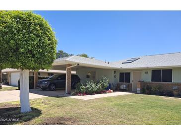 Charming single-story home featuring a covered carport and a well-maintained front yard with a beautiful, rounded tree at 10721 W Mission Ln, Sun City, AZ 85351