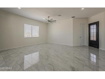 Spacious living room with high ceilings, modern ceiling fan, and stylish tile flooring at 13430 S Garnet Rd, Buckeye, AZ 85326