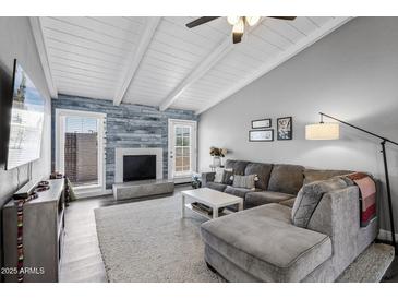 Bright living room with vaulted ceilings, modern decor, a decorative fireplace, and a comfortable sectional sofa at 4502 W Continental Dr, Glendale, AZ 85308