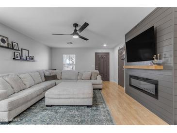 Open living room with a large sectional sofa, modern ceiling fan and electric fireplace at 48069 N Rico Way, Gold Canyon, AZ 85118