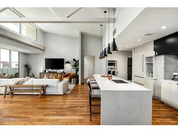 Bright, open-concept living area showcasing modern kitchen, bar seating, hardwood floors, and contemporary decor at 5455 E Lincoln Dr # 3006, Paradise Valley, AZ 85253