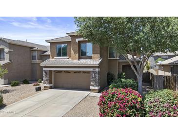 Inviting two-story home with stone accents, a two-car garage, mature landscaping, and a blooming pink bush at 1162 E Ranch Ct, Gilbert, AZ 85296