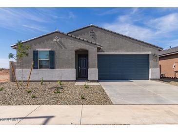 Charming single-story home with a gray stucco exterior, gray roof and a 2-car garage, and low-maintenance landscaping at 16004 W Honeysuckle Dr, Surprise, AZ 85387