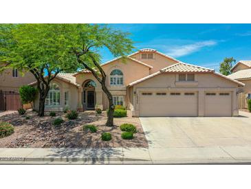 Charming home featuring a three car garage, desert landscaping, and a beautiful shade tree at 19506 N 73Rd Ave, Glendale, AZ 85308