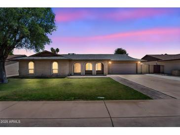 Charming single-story home with a manicured lawn and arched entryway at twilight at 2025 E Magdalena Dr, Tempe, AZ 85283