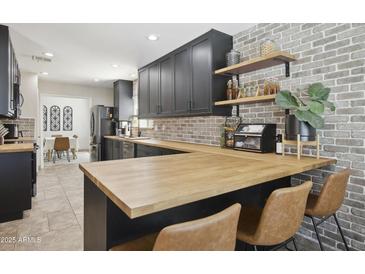 Charming kitchen features butcher block counters, brick accents, stainless appliances, and custom cabinets at 4137 W Cielo Grande --, Glendale, AZ 85310