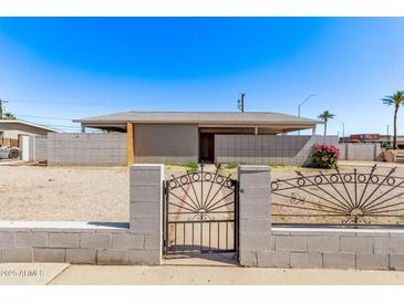 Modest single-story home featuring a gravel front yard and gated block fence at 5902 W Orange Dr, Glendale, AZ 85301