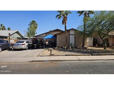 Modest single-story home with mature trees, a covered carport, and off-street parking in front of the house at 604 W Emelita Ave, Mesa, AZ 85210