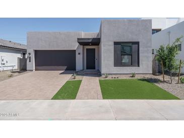 Modern home exterior with a dark garage door, brick driveway and minimalist landscaping at 7956 W Griswold Rd, Peoria, AZ 85345
