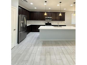 Modern kitchen features dark cabinets, stainless steel appliances, white countertops, and pendant lighting at 1241 E Palo Verde Dr, Casa Grande, AZ 85122