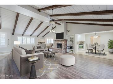 Bright living room boasts wood beam ceiling, brick fireplace, and open layout to dining area and kitchen at 2178 E Golf Ave, Tempe, AZ 85282
