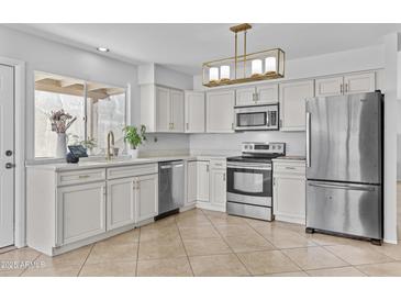Bright kitchen featuring stainless appliances, white cabinets, and stylish lighting at 2313 N 87Th Way, Scottsdale, AZ 85257