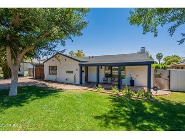 Charming single-story home featuring lush green lawn, mature trees, and a cozy covered front porch at 317 E Orange Dr, Phoenix, AZ 85012