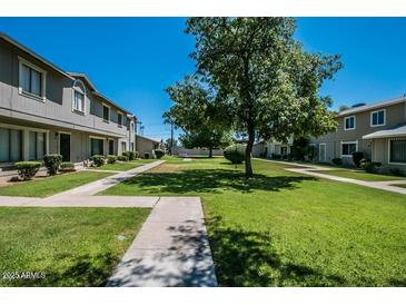 Exterior shows a community with green grass, trees, and light grey buildings on a clear, sunny day at 2645 W Elm St, Phoenix, AZ 85017