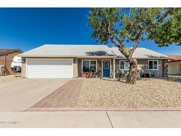 Charming single-story home featuring a well-maintained lawn, a blue front door, and a two car garage at 18233 N 55Th Dr, Glendale, AZ 85308