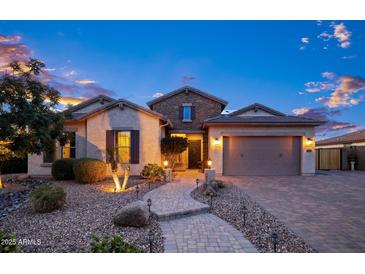 Charming single-story home showcasing a stone facade, manicured landscape, and a welcoming brick pathway at 18544 W Devonshire Ave, Goodyear, AZ 85395