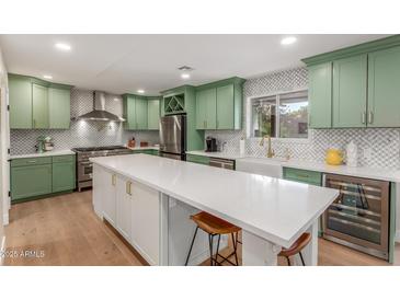Bright kitchen features custom green cabinets, stainless appliances, a white backsplash, and an oversized center island at 2402 E Cinnabar Ave, Phoenix, AZ 85028