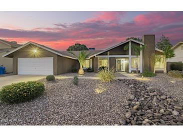 Charming home featuring desert landscaping, a chimney, and a two-car garage against a stunning pink sky at dusk at 2422 W Acoma Dr, Phoenix, AZ 85023