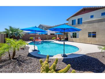 Inviting backyard pool area with blue umbrellas, lush greenery, and a beautiful sunny sky at 3247 E Creosote Ln, Gilbert, AZ 85298