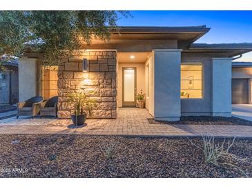 Charming home featuring a stone facade and a well-lit entrance with a lovely garden at 13186 W Via Dona Rd, Peoria, AZ 85383