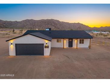Beautiful single-story home with a dark gray garage door and mountain views at 16630 N Slate Ln, Maricopa, AZ 85139