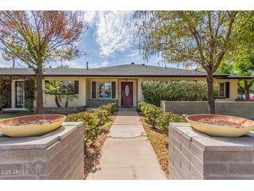 Charming single-story home featuring a manicured front yard with mature trees and a welcoming red front door at 2938 N 18Th Ave, Phoenix, AZ 85015