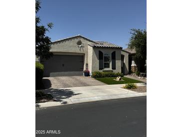 Charming single story home with a well-manicured lawn, a grey garage door, and desert landscaping at 10704 E Twister Ave, Mesa, AZ 85212