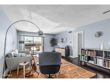 Stylish living room with hardwood floors, light blue walls, a ceiling fan, and sliding glass doors to a patio at 3825 E Camelback Rd # 152, Phoenix, AZ 85018