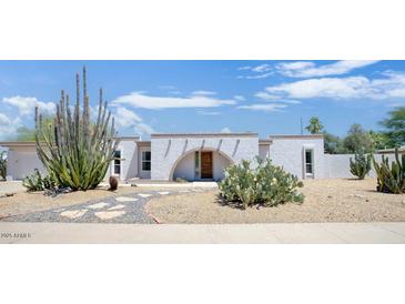 Charming single-story home with unique desert landscaping, featuring cacti and a decorative arched entrance at 4032 E Cannon Dr, Phoenix, AZ 85028