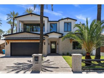 Stunning two-story home featuring a brick exterior, black accents, and lush palm tree landscaping at 4301 E Sells Dr, Phoenix, AZ 85018