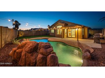 Backyard with a beautiful rock-feature pool, string lights, and a covered patio for relaxing evenings at 6309 W Hughes Dr, Phoenix, AZ 85043