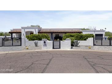 Charming stucco home featuring a tile roof, desert landscaping, and gated driveway at 10024 N 61St Pl, Paradise Valley, AZ 85253