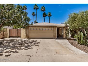 Tan brick home with two-car garage, desert landscaping, and palm trees in front at 2256 S Las Flores --, Mesa, AZ 85202